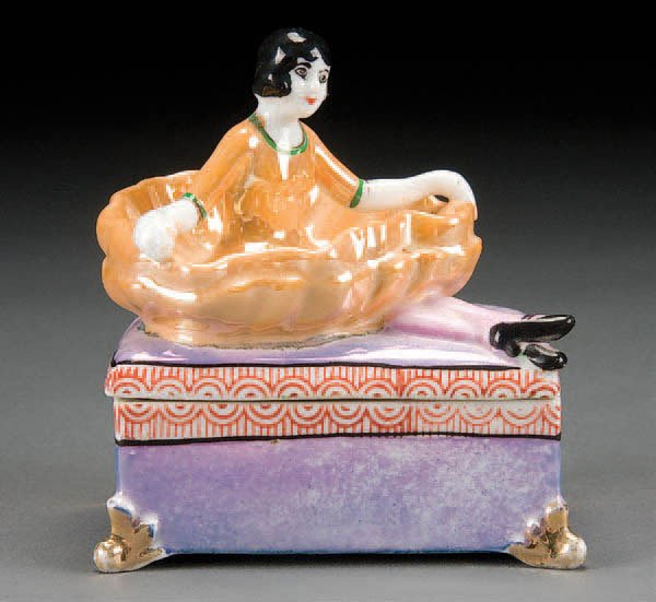 NORITAKE FIGURAL COVERED DRESSER BOX: A HAND PAINTED NORITAKE FIGURAL COVERED DRESSER BOX circa 1930's, with figure of a ballerina on lid. Magenta cherry blossom Japan mark. Height 4.25 inches. Estimate $100-$200