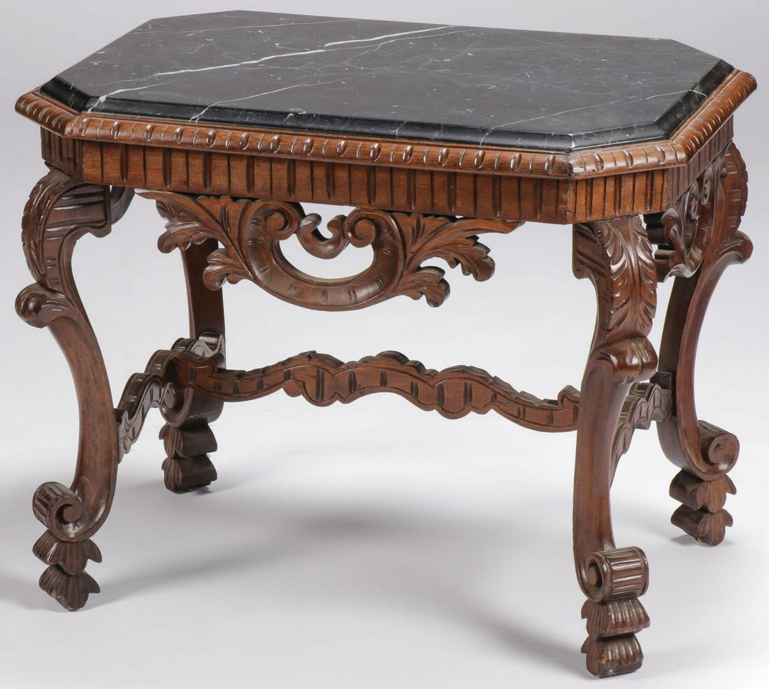 A CARVED MARBLE TOP TABLE, C. 1900: A CARVED MARBLE TOP TABLE, C. 1900. Comprising a black beveled marble inset top above geometrically designed border and intricately carved apron standing on four cabriole legs terminating in scrolled 