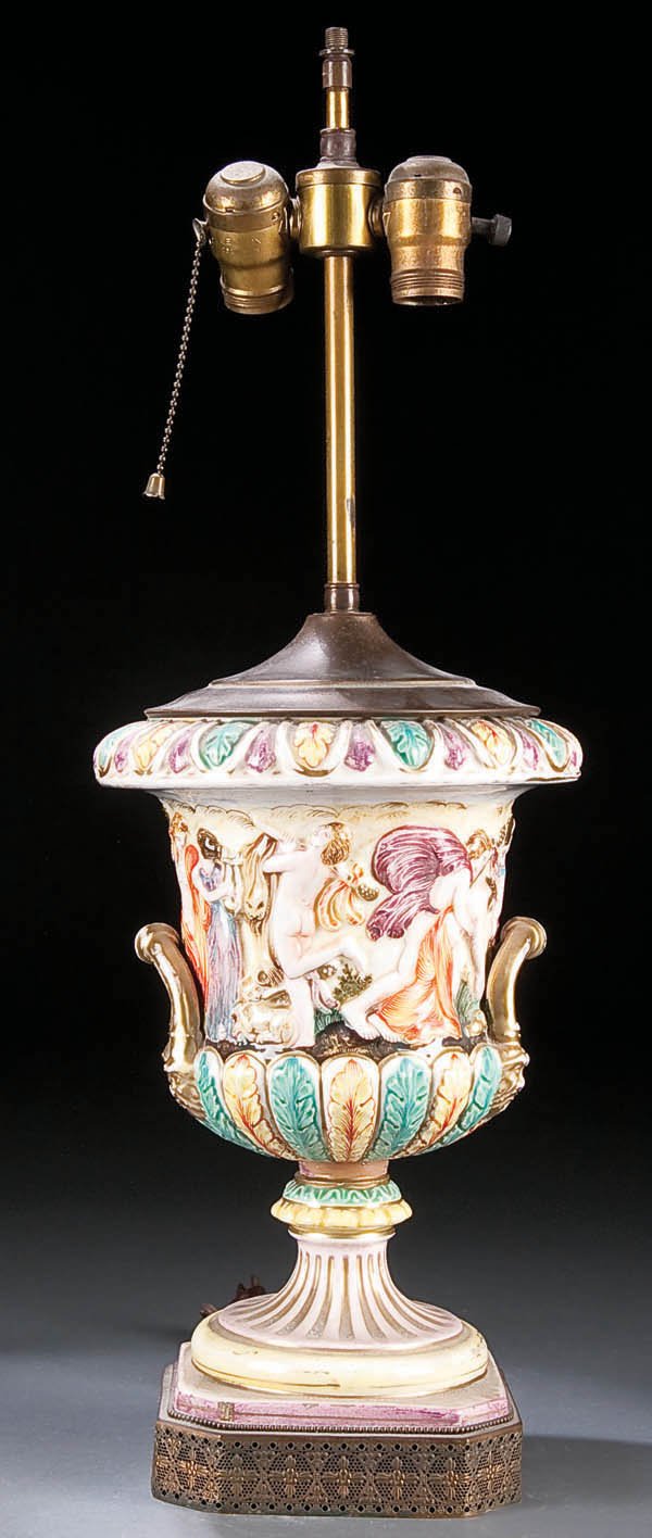 A CAPODIMONTE PORCELAIN HANDLED CAMPAGNA URN circ: A CAPODIMONTE PORCELAIN HANDLED CAMPAGNA URN circa 1900, with relief molding and fitted as a table lamp, some restorations. Height of urn 12 inches. Estimate $75-$150