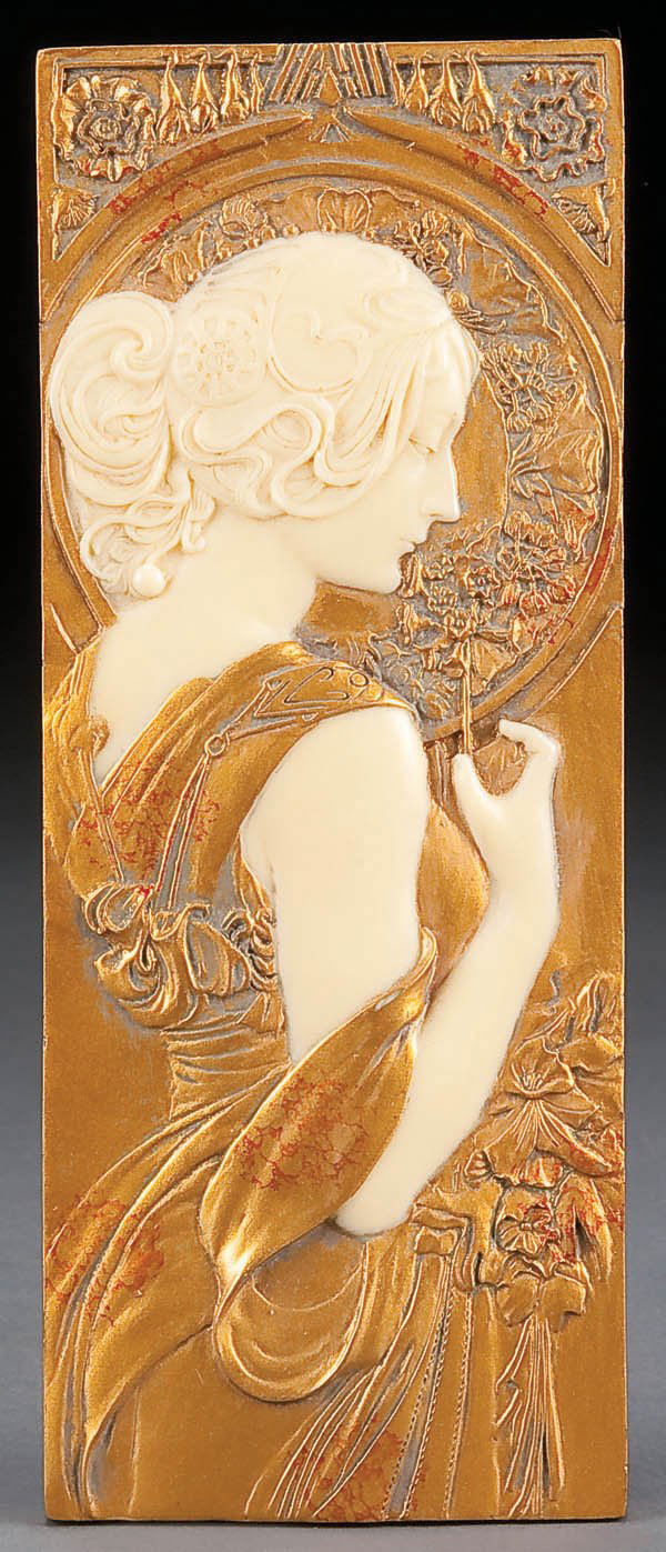 A FAUX IVORY AND GILT FINISH EMBOSSED ART NOUVEAU: A FAUX IVORY AND GILT FINISH EMBOSSED ART NOUVEAU PLAQUE OF A YOUNG BEAUTY, last half 20th century, after Mucha, 9.5 x 3.75 inches. Estimate $40-$80
