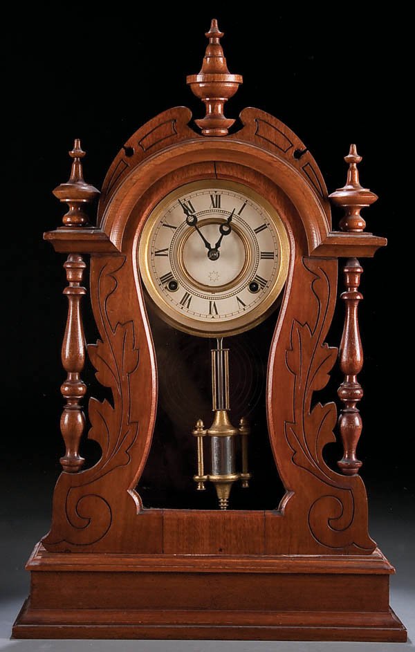 A VICTORIAN WALNUT SHELF CLOCK, late 19th century: A VICTORIAN WALNUT SHELF CLOCK, late 19th century, with incised scalloped case and turned finials. Height 23 inches. Estimate $100-$200