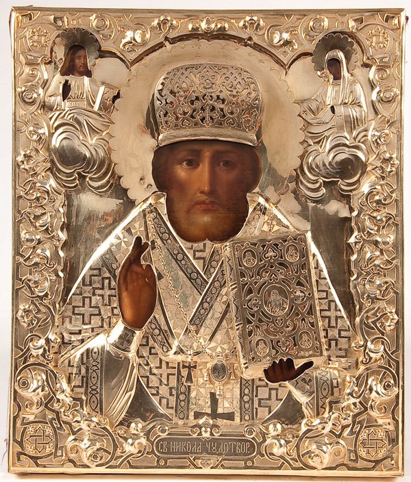 A RUSSIAN ICON OF SAINT NICHOLAS, 19TH CENTURY. : A RUSSIAN ICON OF SAINT NICHOLAS, 19TH CENTURY. Executed in the Italianate style, Nicholas holds the Gospels and delivers a blessing, overlaid with an ornate heavily repoussed and chased silver-gilt r