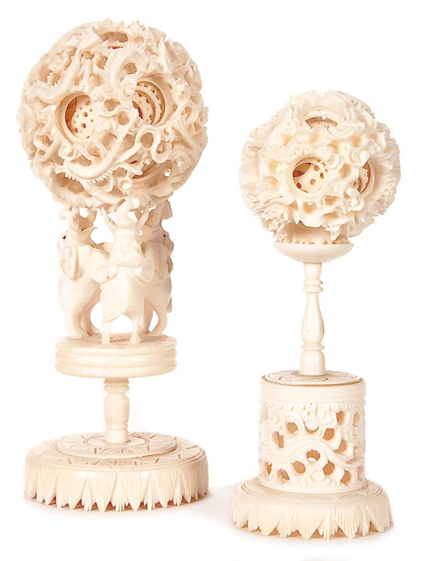 TWO ORIENTAL CARVED IVORY PUZZLE (MYSTERY) BALLS: TWO ORIENTAL CARVED IVORY PUZZLE (MYSTERY) BALLS, MID 20TH CENTURY. Each multi-layered spherical form with carved reticulated dragons, diameter 2 inches (5 cm) and 2.5 inches (6.5 cm). Raised on a car