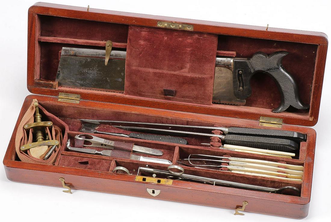 CIVIL WAR CASED SURGEON'S KIT: CIVIL WAR CASED SURGEON'S KIT. Comprising a typical mahogany case set with a variety of instruments including a checkered horn handled bone saw, and flesh knives, made in Scotland. As well as a set of