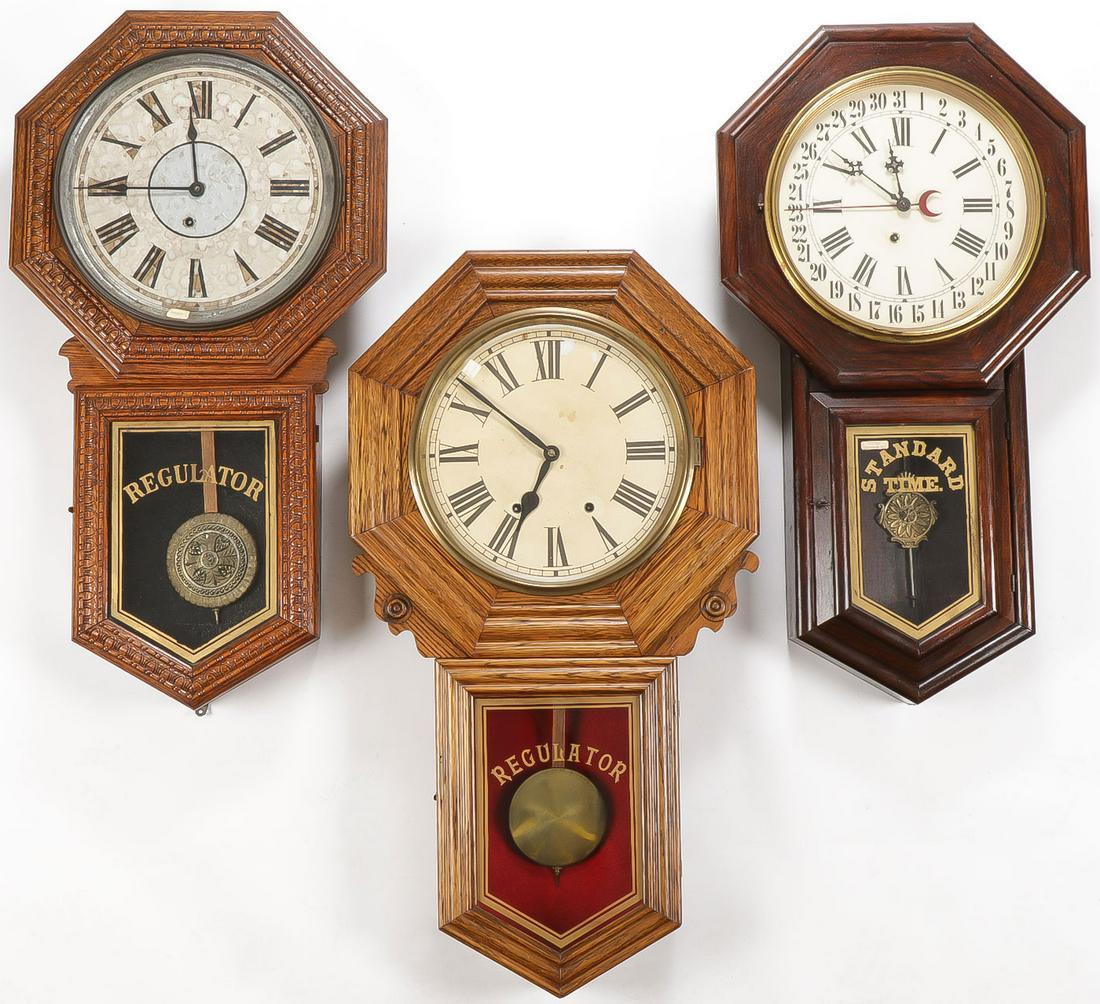 3 WALL REGULATORS: 3 WALL REGULATORS. Comprising three drop octagon wood case clocks all with glazed fronts opening to reveal metal clock faces with Roman numerals two of the clocks with Ingraham maker's mark. Greatest