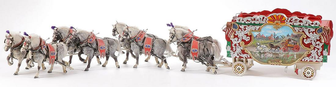 A HORSE-DRAWN CIRCUS WAGON MODEL: A HORSE-DRAWN CIRCUS WAGON MODEL. Comprising an ornate painted wooden toy circus wagon, depicting a scene of American buffalo on one side and a stagecoach on the other being pulled by a team of eight 