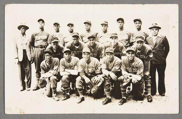 BLACK MEMORABILIA: BASEBALL REAL PHOTO POSTCARD: AN INDIANAPOLIS CLOWNS NEGRO LEAGUE BASEBALL TEAM REAL PHOTO POSTCARD mid 20th century. Depicting the team and managers in uniform. Good condition with center crease. Postally unused. EKC back.