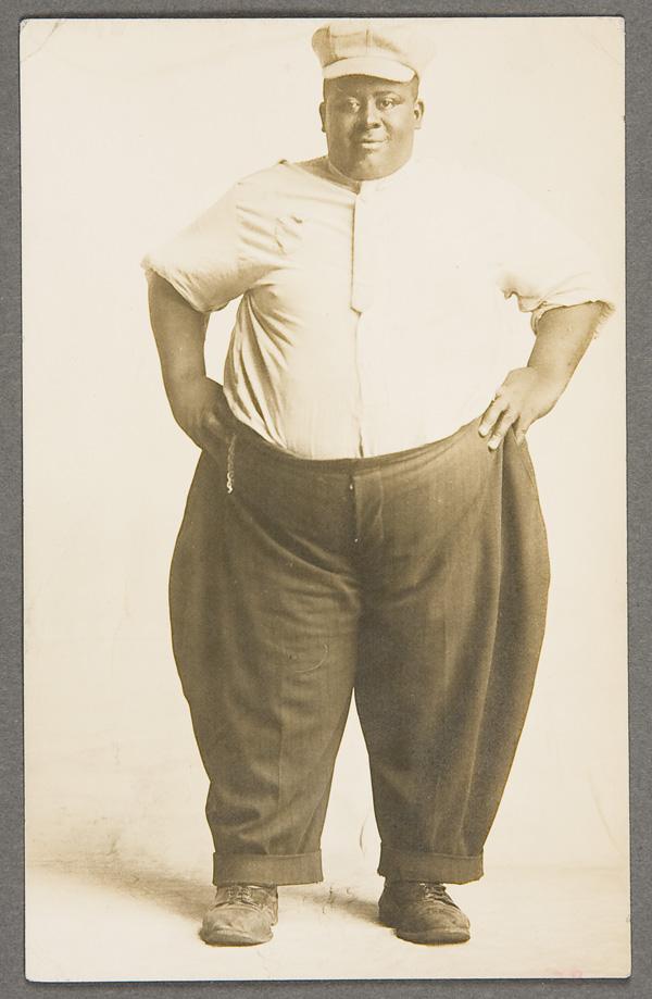 BLACK MEMORABILIA: REAL PHOTO POSTCARD: A FAT BLACK MAN REAL PHOTO POSTCARD early 20th century. Postally unused, Azo back. Slightly trimmed.