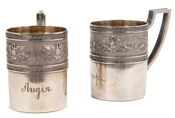 PAIR RUSSIAN FABERGE SILVER CUPS: A PAIR OF FABERGE SILVER CUPS, Moscow circa 1900. Of cylindrical shape, the borders embossed with swans with splayed wings on a matted ground, the edges with a Greek key pattern, gilded interiors and 