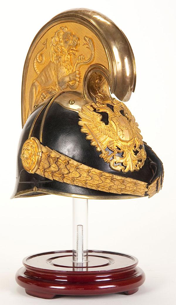 AUSTRIAN M1905 OFFICER HELMET: AN AUSTRIAN MODEL 1905 DRAGOON OFFICER'S HELMET. Black leather covered metal body, and high brass comb with lion embossed sides, gold washed eagle plate and chin scales. Silk lining and leather sweatb