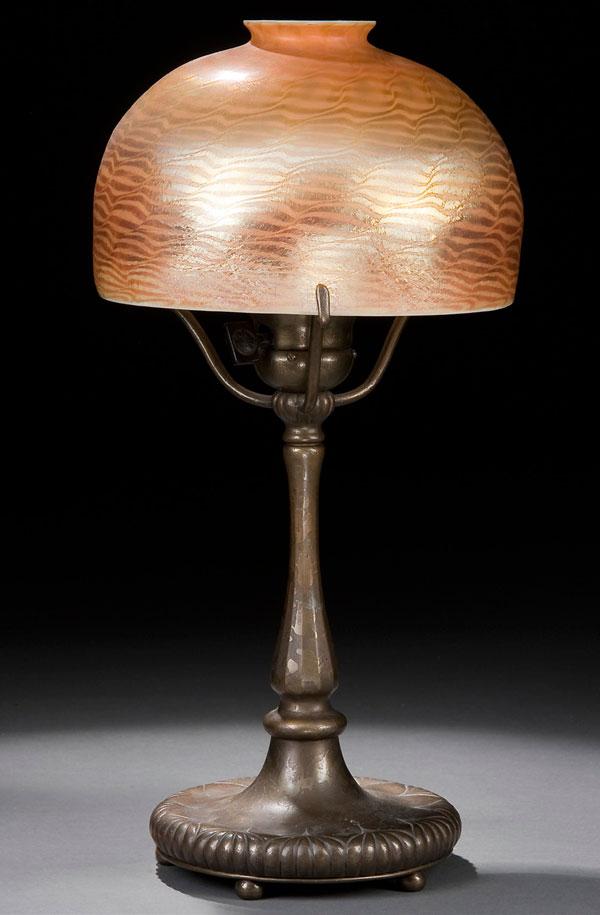 TIFFANY STUDIOES FAVRILE GLASS DESK LAMP: A TIFFANY STUDIOS FAVRILE GLASS AND BRONZE DESK LAMP early 20th century. The etched bronze base below a gold iridized opalescent domed shade with an undulating damascene pattern. The base stamped "Tif