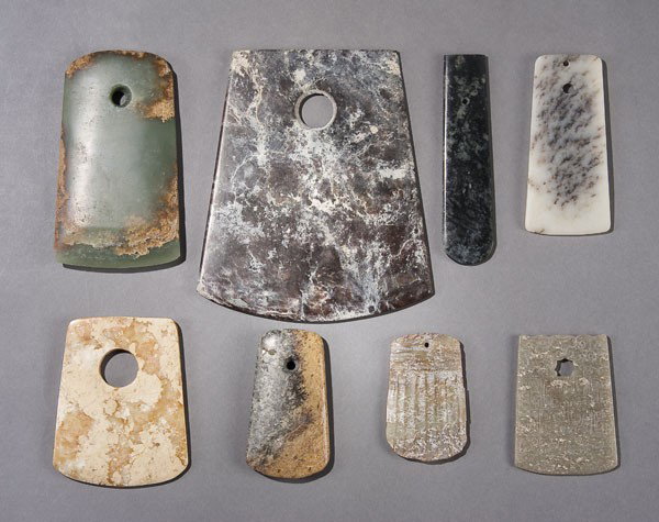 8 CHINESE CARVED JADE & HARDSTONE AXE BLADES: A GROUP OF 8 CHINESE CARVED JADE & HARDSTONE ARCHAIC & NEOLITHIC STYLE PENDANTS & CEREMONIAL AXE BLADES in various colors of jade including white, celadon & brown. Largest 6.5 inches x 5.5 inches.