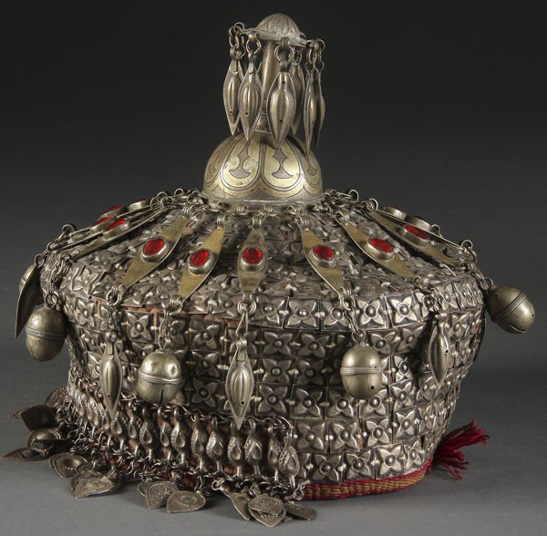 FINE HIMILAYAN REGIONAL CROWN: A FINE HIMILAYAN REGIONAL CROWN 19th century. The woven and stitched skull cap overlaid with nickel silver rosettes, embossed pendant fringe and bells, below ruby colored cabachons and a gilt niello f