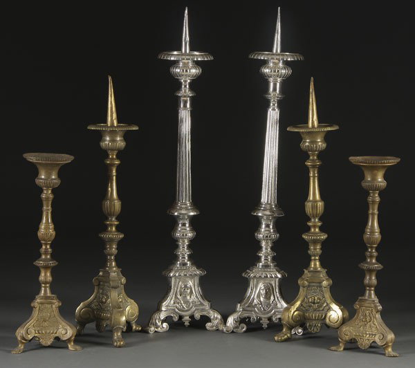 6 ALTAR CANDLE STANDS: A GROUP OF 6 ALTAR CANDLE STANDS CIRCA 1800-1900. Comprising a pair of matching bronze candle sticks with wide drip pan and 3-sided base displaying the Sacred Heart and winged cherubs, 15.5 inches. A 