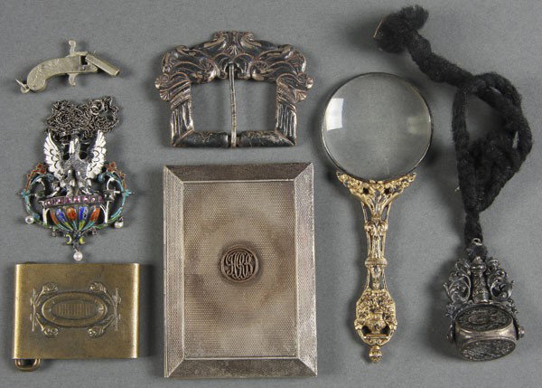 5-PC EUROPEAN DECORATIVE SILVER GROUPING: A 5-PIECE EUROPEAN DECORATIVE SILVER GROUPING circa 1850-1920. Consisting of a gilt handled magnifying glass, an enameled & jeweled pendant of a pelican feeding young, a rotating seal, a silver buckle