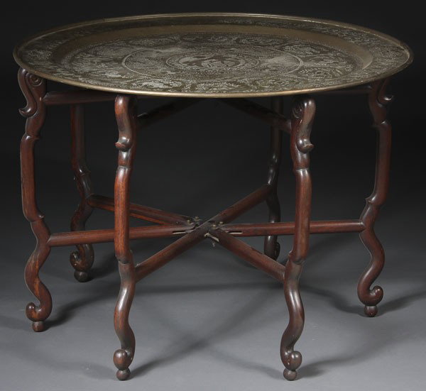 CHINESE BRASS & MAHOGANY FOLDING TABLE: A CHINESE BRASS & MAHOGANY FOLDING TABLE early 20th century. The 6-legged carved wood folding stand supporting a brass tray with incised dragon and Zodiac figures. Diameter 36 inches.