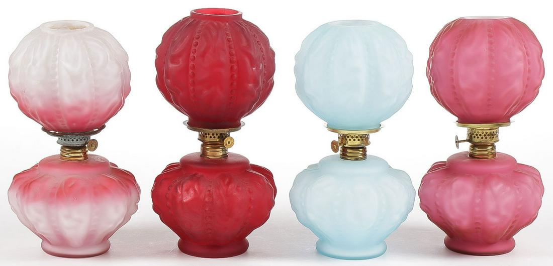 4 MINIATURE CASED AND SATIN GLASS KEROSENE LAMP: FOUR MINIATURE CASED AND SATIN GLASS KEROSENE LAMPS. Each in beaded drape pattern and in four different colors including clear to red, ruby ice blue and pink. Greatest height 9.25 inches. SHIPPING NOT