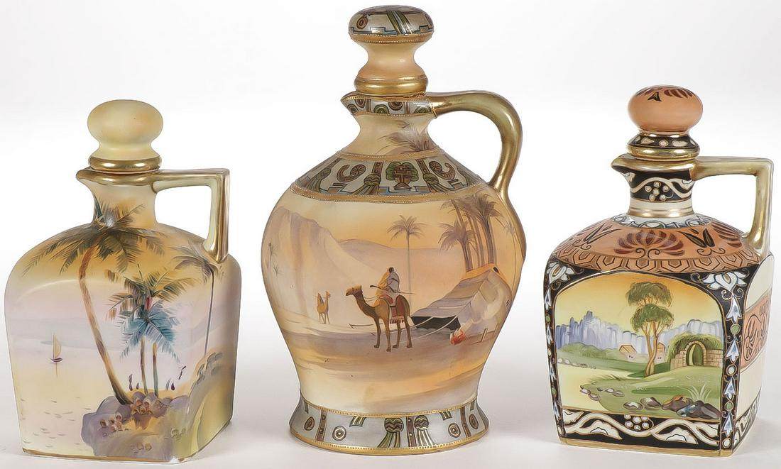 THREE LOVELY NIPPON PORCELAIN JUGS: THREE LOVELY NIPPON PORCELAIN JUGS. Comprising a large wine jug with Egyptian motif, as well as a similarly decorated whiskey jug and another whiskey jug with landscape scene. Each with green "M" in w