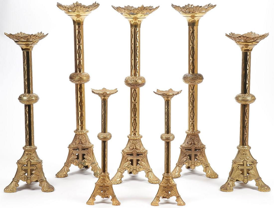 7 GILT BRONZE ALTAR CANDLE STANDS: 7 GILT BRONZE ALTAR CANDLE STANDS. All matching designs with tripod bases faced with crosses and large leaf form drip pans. Greatest height 30.5 inches. SHIPPING NOTICE: Jackson's is your sole and onl