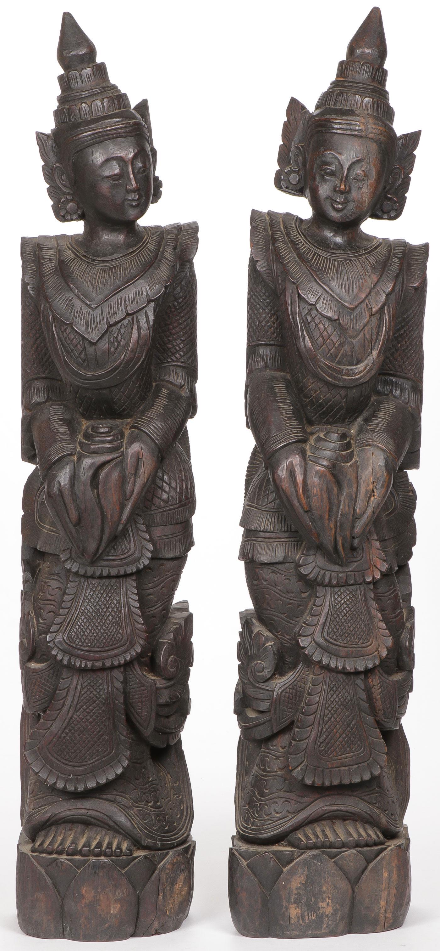 PAIR OF CARVED WOOD ASIAN FIGURES: PAIR OF CARVED WOOD ASIAN FIGURES. Comprising a pair of full-length figures in ornate dress, each holding a seashell and standing on a lotus base. Overall height 37.25 inches. SHIPPING NOTICE: Jackson
