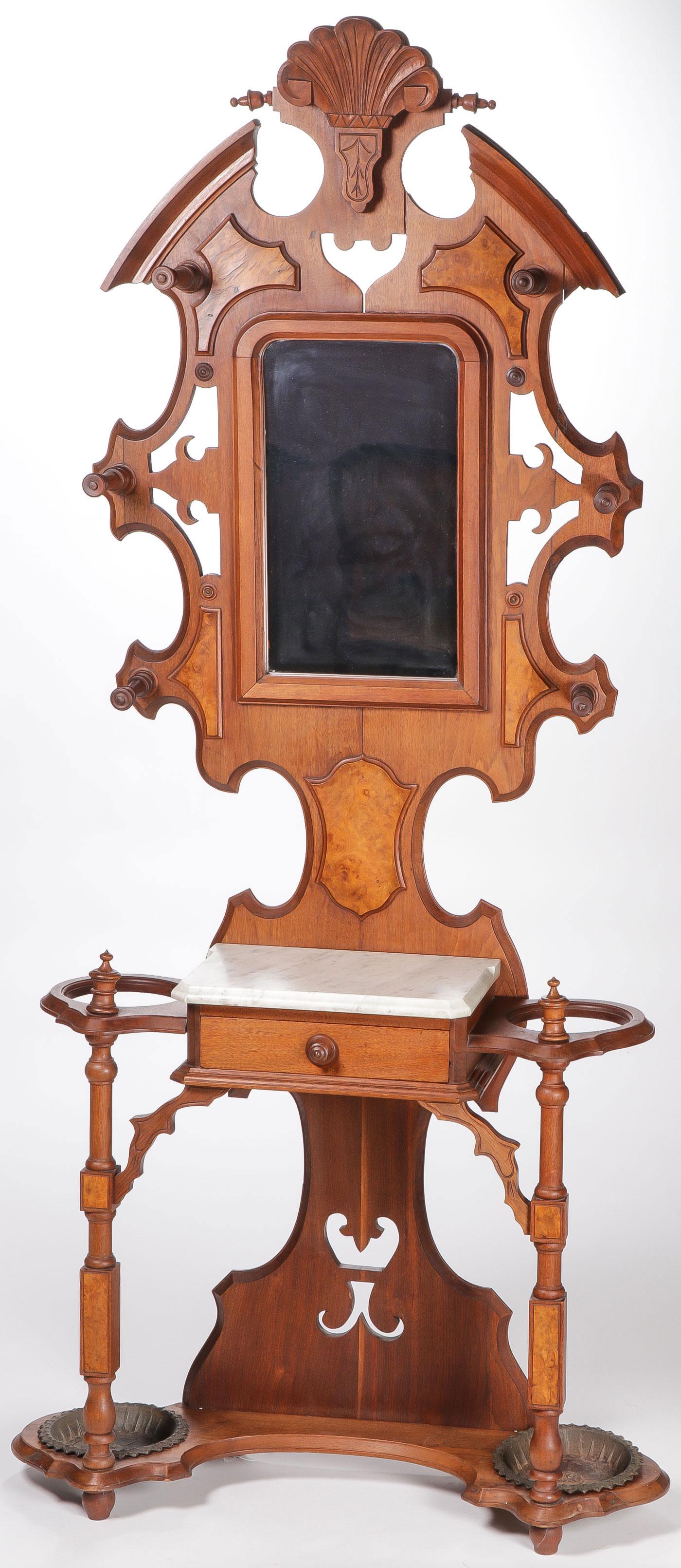 A WALNUT VICTORIAN HALL TREE: A WALNUT VICTORIAN HALL TREE. Comprising a shell form crest above a mirrored back surrounded by six turned coat hooks giving way to a marble top shelf above a single drawer flanked by two umbrella sta