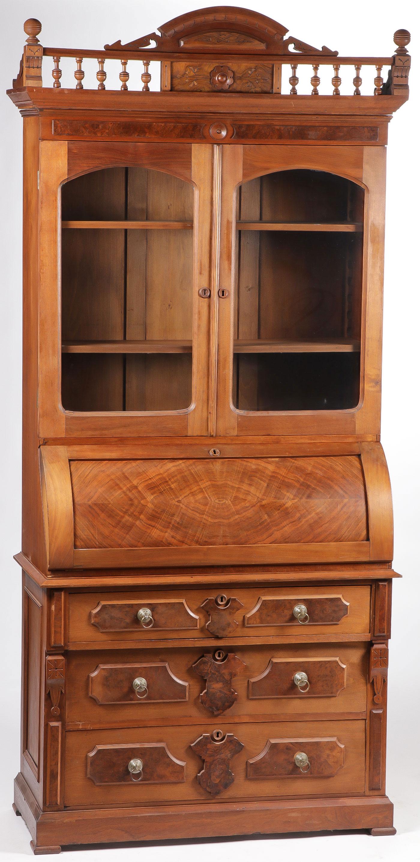 A SLANT FRONT WALNUT SECRETARY BOOKCASE: A SLANT FRONT WALNUT SECRETARY BOOKCASE. Comprising a two-sectioned secretary bookcase with ornately carved balcony above glazed front upper section and a slant front desk opening to reveal a writing 