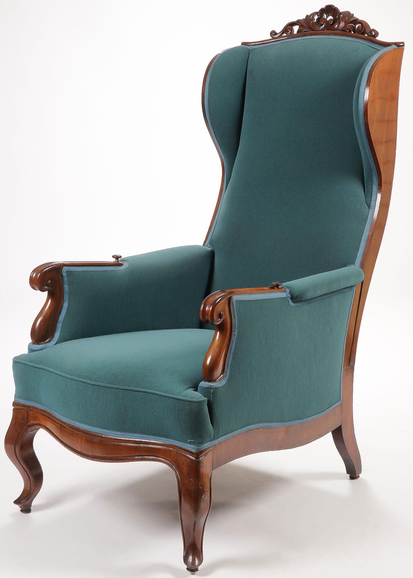 A RARE VINTAGE RECLINING ARMCHAIR: A VINTAGE RECLINING ARMCHAIR. Comprising a pierced carved crest above an upholstered back, seat, and arms all raised on four legs. The arms are set with release buttons which allow the chair to reclin