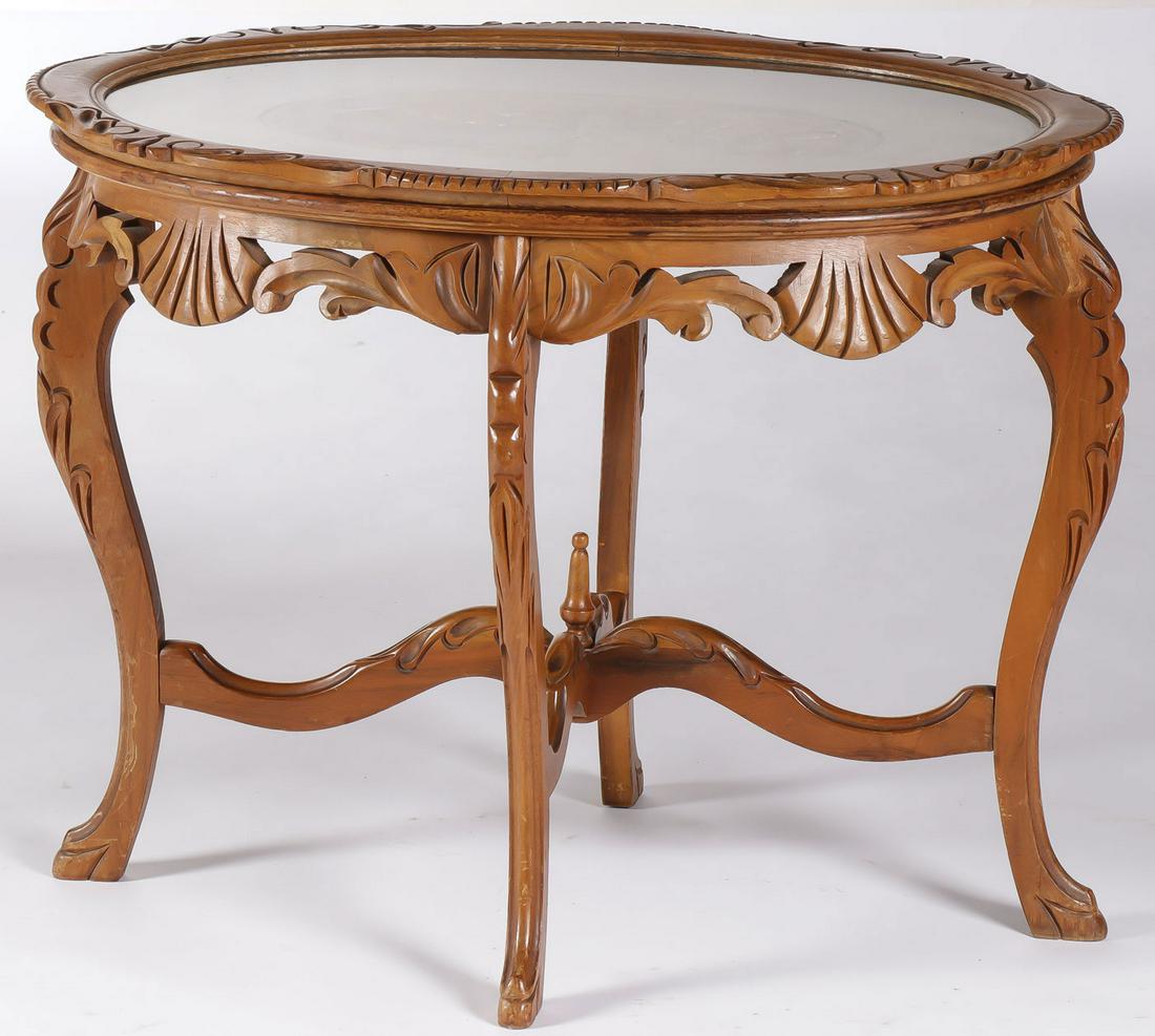 A CARVED GLASS TRAY TOP COFFEE TABLE: A CARVED GLASS TRAY TOP COFFEE TABLE. Comprising an ornately carved coffee or tea table depicting a landscape with castle in foreground with pierced carved apron and four cabriole legs connected by X