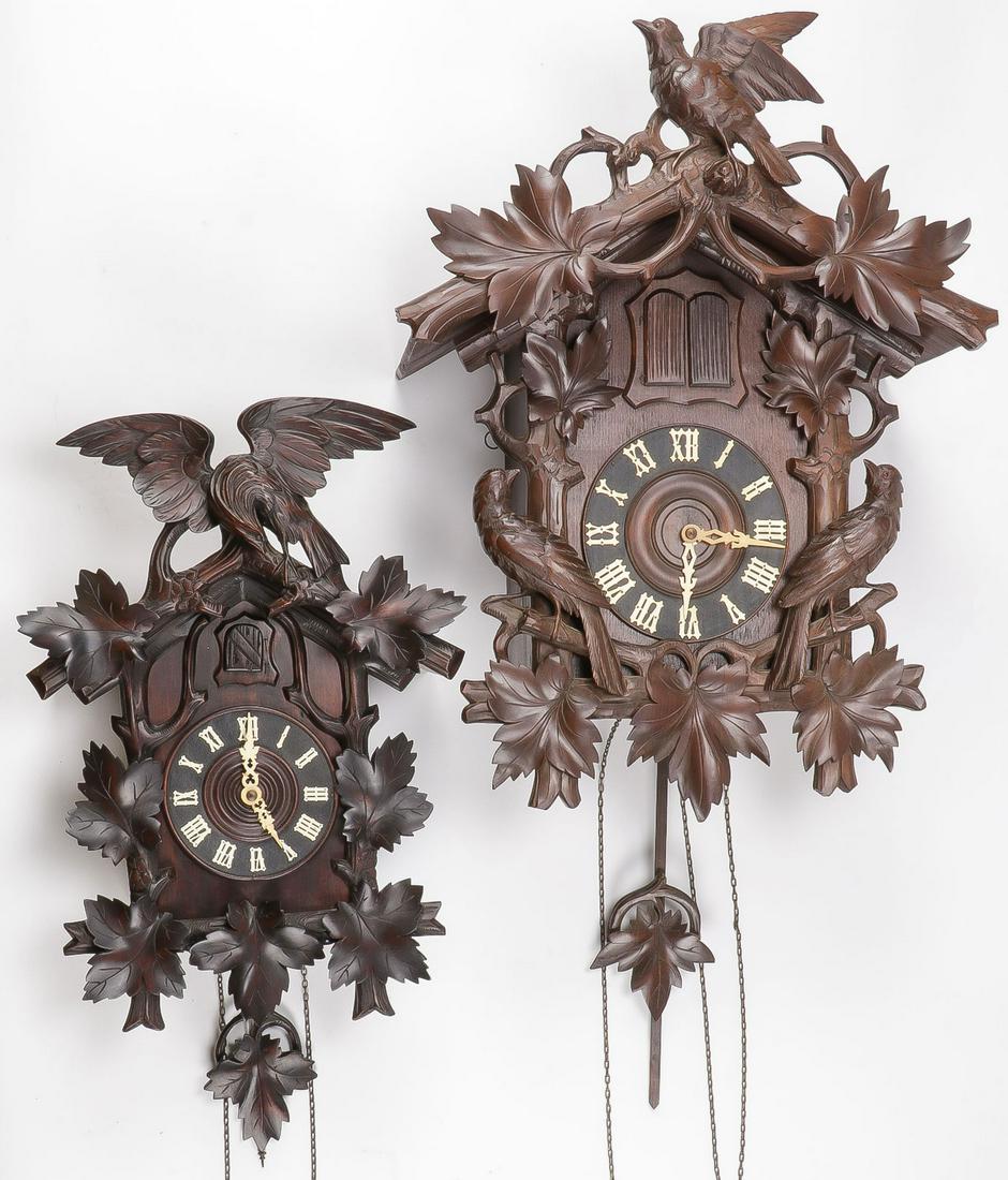 A PAIR BLACK FOREST CUCKOO CLOCKS: A PAIR BLACK FOREST CUCKOO CLOCKS. Comprising a pair of large and impressive Black Forest Swiss carved cuckoo clocks circa 1900 with Roman numeral dials and carved bird and oak leaf surrounds, and lea