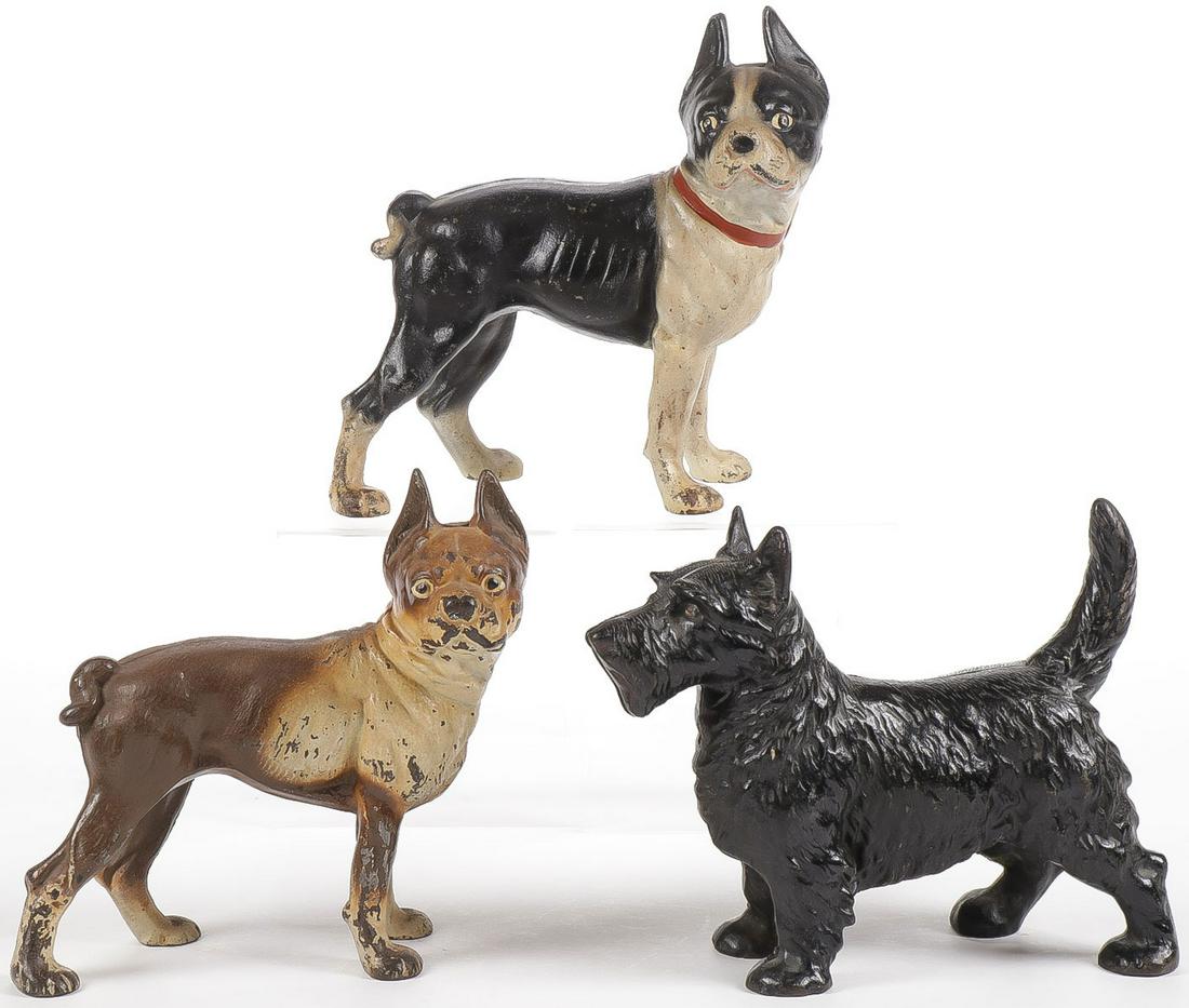 VINTAGE CAST IRON DOG DOORSTOPS: VINTAGE CAST IRON DOG DOORSTOPS. Comprising three polychrome cast iron doorstops, two modeled as bulldogs, one as a Scottish Terrier. Greatest length 11 inches. SHIPPING NOTICE: Jackson's is your sole