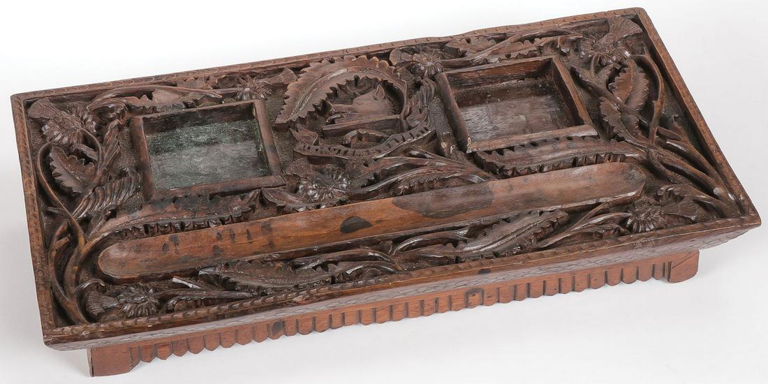 CARVED ANGLO-INDIAN DESK STAND: CARVED ANGLO-INDIAN DESK STAND. Comprising an attractive carved wood desk stand circa 1860 with integral pen rest and receptacles for ink wells and at center a Heraldic shield with boar's head and Lat