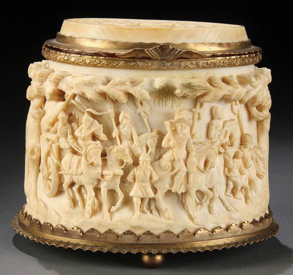 SOUTH GERMAN CARVED IVORY AND GILT-COPPER BOX: A FINE SOUTH GERMAN CARVED IVORY AND GILT-COPPER MOUNTED LIDDED BOX, the sides carved in high relief depicting scenes of travelers in a wooded landscape. The hinged lid with gilt copper mounts and ins