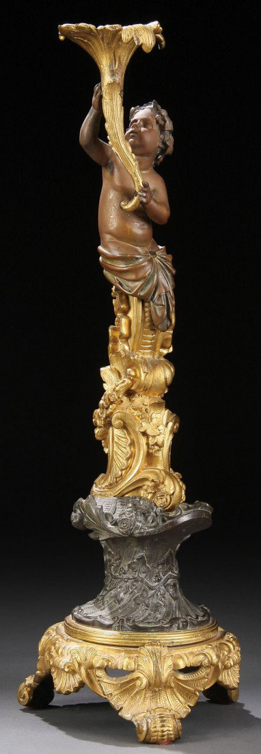 FRENCH PATINATED & GILT BRONZE FIGURAL CANDLE STAN: A FRENCH PATINATED AND GILT BRONZE FIGURAL CANDLE STAND, 19th century. Depicting a Bacchanalian putto holding a lily form candle socket raised on a scrolled pedestal. Height 20 inches.