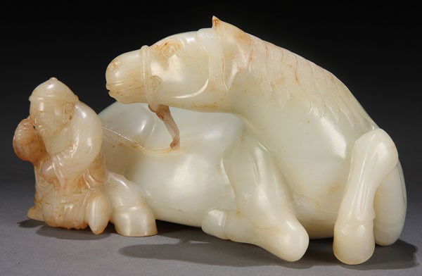 CHINESE CARVED WHITE JADE MING STYLE HORSE QING: A FINE CHINESE CARVED WHITE JADE FIGURE OF A RECUMBENT MING STYLE HORSE, QING DYNASTY. Depicting an animated alert horse with suspended reins held by an unmounted groom wearing leather boots with well