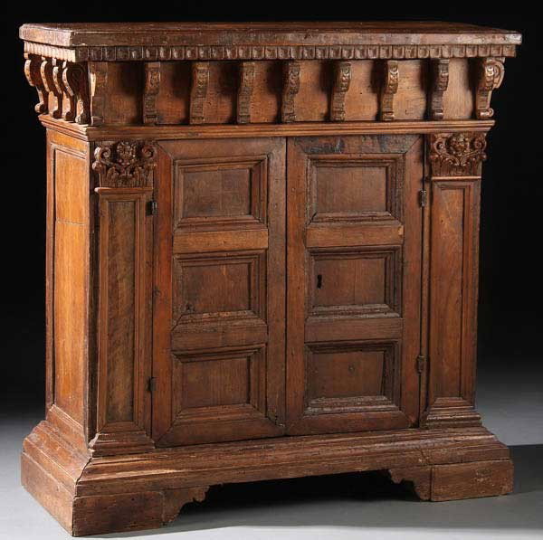 ITALIAN RENAISSANCE WALNUT CREDENZA, 16TH/17TH C: AN ITALIAN RENAISSANCE WALNUT CREDENZA, 16TH/17TH CENTURY. With fluted dental molded top edge above applied carved scrolled corbels containing two inconspicuous drawers above two deeply paneled doors 