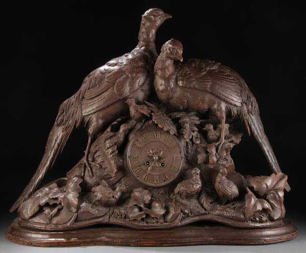 SWISS CARVED BLACK FOREST FIGURAL WOOD CLOCK: A LARGE AND IMPRESSIVE SWISS CARVED "BLACK FOREST" FIGURAL WOOD CLOCK, CIRCA 1900. Depicting large figural pheasants, chicks and foliage on a rockery ground with conforming plinth base. Some minor los