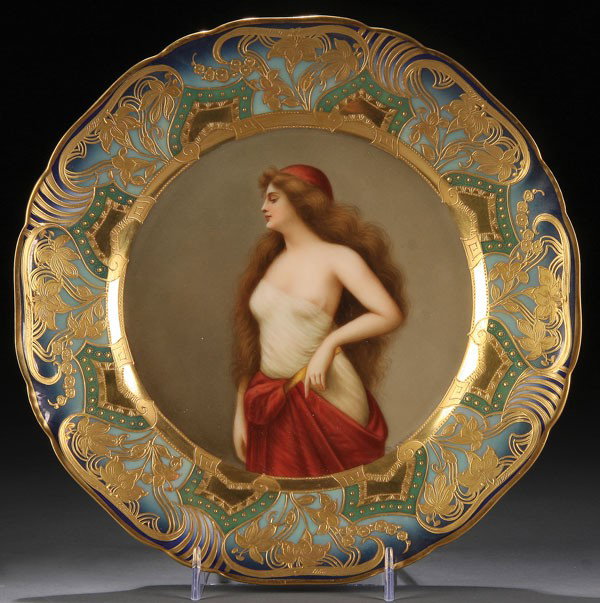 ROYAL VIENNA STYLE WAGNER NUDE PORTRAIT PLATE: A VERY FINE ROYAL VIENNA STYLE WAGNER NUDE PORTRAIT PLATE, CIRCA 1900. Depicting a partially clothed young beauty within a raised gilt floral rim on a shaded blue ground, beehive marked underglaze and