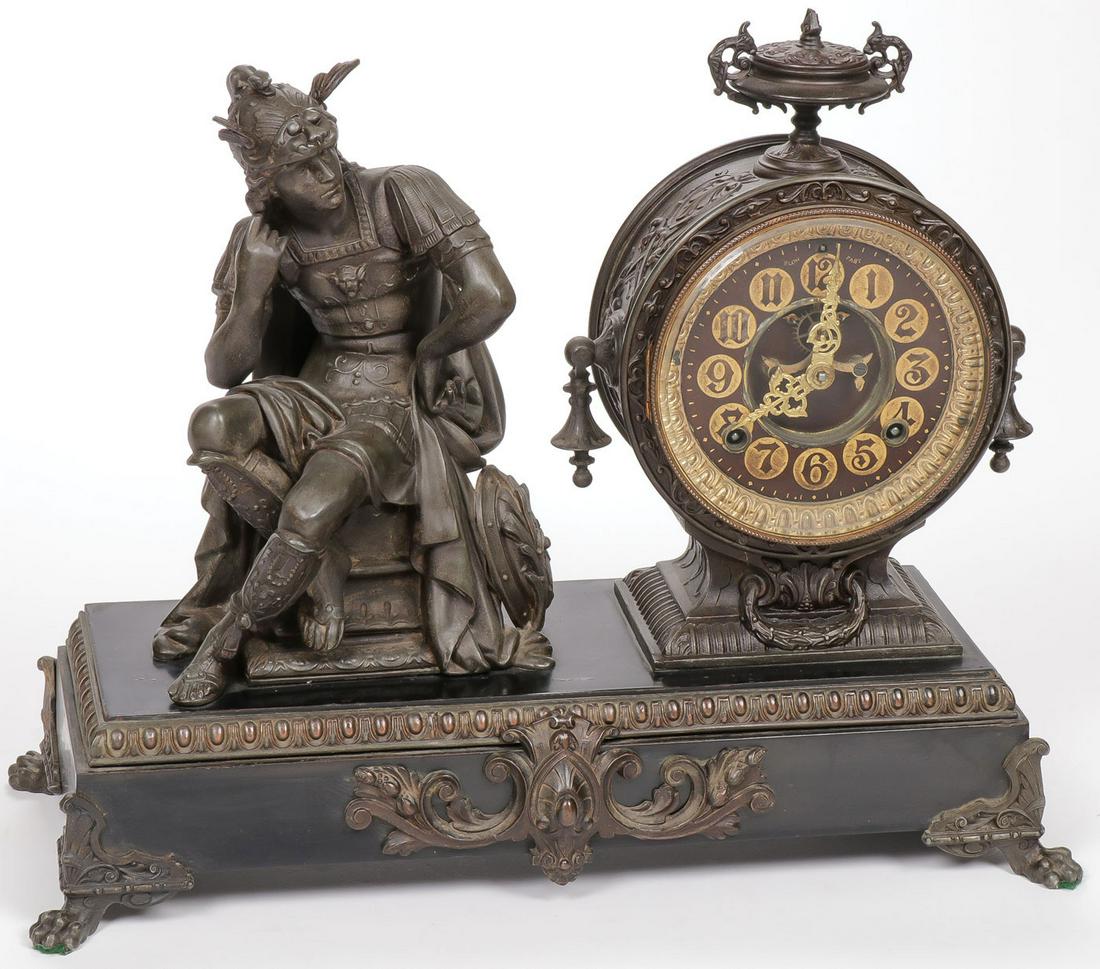 ORNATE ANSONIA FIGURAL MANTEL CLOCK: ORNATE ANSONIA FIGURAL MANTEL CLOCK. Each corner set with an ornate paw foot, the faux marble enameled metal rectangular base set with ornate key wind Ansonia clock flanked by a finely sculpted Roman 