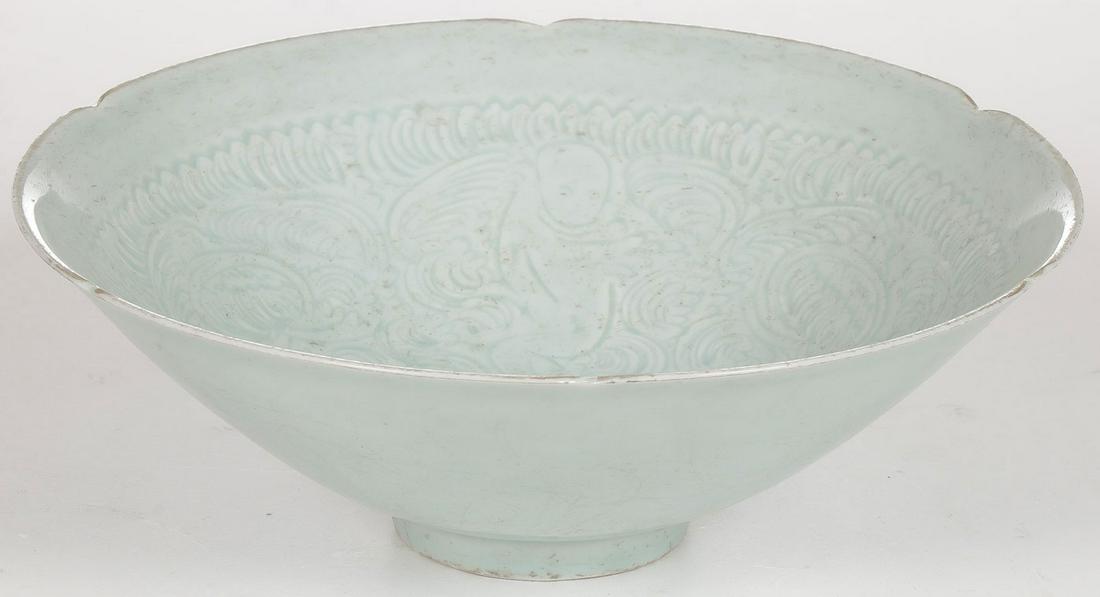CHINESE CELADON PORCELAIN BOWL: CHINESE CELADON PORCELAIN BOWL. Resting on a ring foot with flared sides, scalloped rim and the interior incised with figures amidst clouds. Probably 18th or 19th century. Diameter 8.5 inches (21 cm),