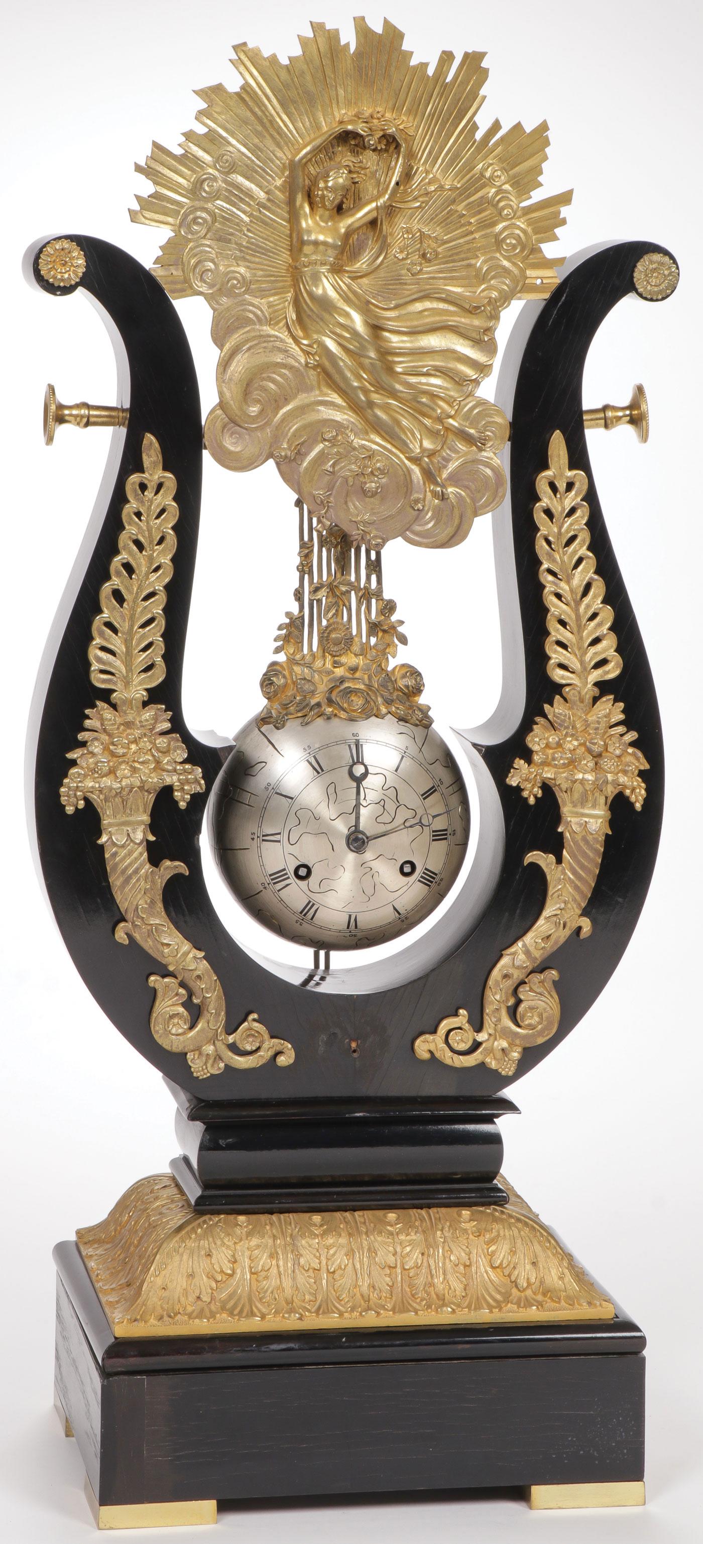 A REGENCY LYRE SHAPED MYSTERY CLOCK: A REGENCY LYRE SHAPED MYSTERY CLOCK. The ebonized laminated wood case in the form of a lyre with gilt bronze acanthus leaf insert on base upon which rests the lyre with cornucopia gilt bronze mounts a