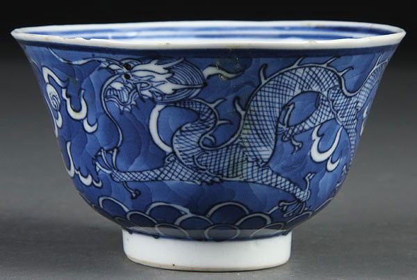 CHINESE BLUE/WHITE DECORATED TEA CUP: A CHINESE BLUE/WHITE DECORATED TEA CUP, 19TH/20TH CENTURY. With dragon and cloud form decoration, raised on a circular foot. Apocryphal Kangxi six-character mark on base. Hairline. Diameter 4 inches (