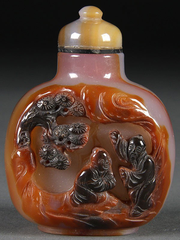2 CHINESE CARVED AGATE SNUFF BOTTLES, 20TH C: A PAIR OF CHINESE CARVED AGATE SNUFF BOTTLES, 20TH CENTURY, in smoky grey and amber colored stone with dark reddish brown highlights, carved with scenes of immortals and attendants. Height 3.25 inches