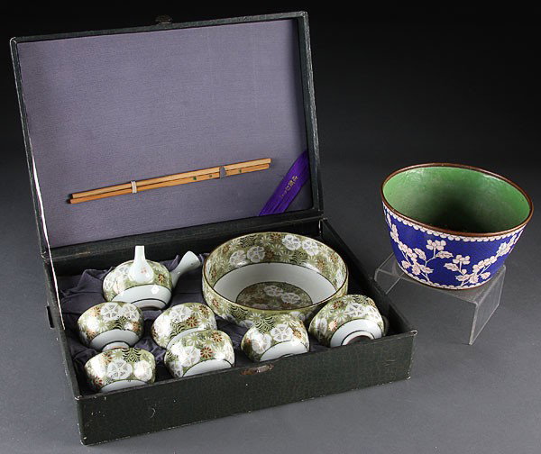 A CHINESE CLOISONNÉ ICE TUB/JARDINIÈRE TEA SET: A CHINESE CLOISONNÉ BRONZE ICE TUB/JARDINIÈRE, EARLY 20TH CENTURY, with white prunus branches on blue ground. Together with a post war cased tea set with matching bowl containing eight pieces. Clois