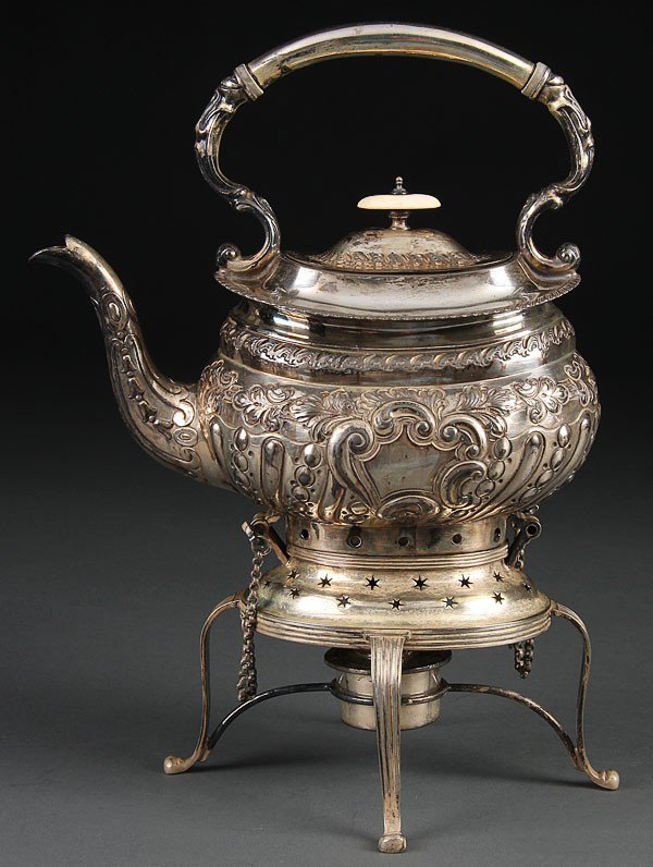 AN ENGLISH SILVERPLATE TILTING HOT WATER KETTLE, : AN ENGLISH SILVERPLATE TILTING HOT WATER KETTLE, EARLY 20TH CENTURY, with repousse scrolled decoration on four-footed warming stand. Height 13 inches (33 cm).