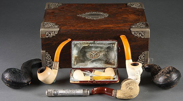 A VICTORIAN OAK CIGAR HUMIDOR, with reticulated e: A VICTORIAN OAK CIGAR HUMIDOR, with reticulated embossed metal attachments. Together with five Meerschaum pipes, one with Turkish facial bust, several Briarwood pipes and other related accessories. Le