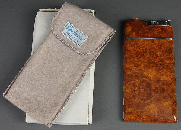 EVANS COMBINATION CIGARETTE CASE LIGHTER CARTIER: AN EVANS COMBINATION CIGARETTE CASE LIGHTER WITH FAUX BURLWOOD GRAIN PANELS, contained in a Cartier felt slipcover and Cartier box. Length 6.75 inches (17 cm).