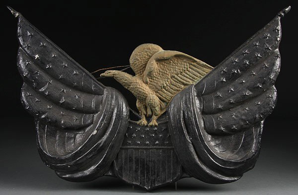 AN EARLY POLYCHROME CAST ALUMINUM EAGLE AND FLAG: AN EARLY POLYCHROME CAST ALUMINUM EAGLE AND FLAG PLAQUE, EARLY 20TH CENTURY. Depicting a painted gilt eagle atop a Union shield with crossed swagged bunting. Length 26 inches.