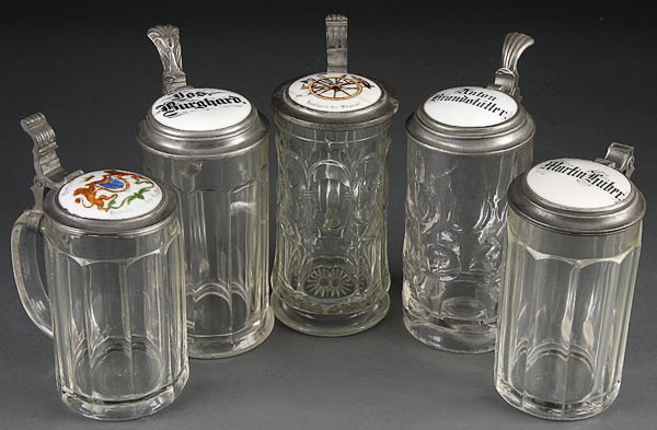 , 5 GERMAN BEER STEINS PRESSED GLASS PORCELAIN: BEER STEINS, FIVE GERMAN PRESSED GLASS AND PORCELAIN LIDDED BEER STEINS, MID TO LATE 19TH CENTURY. Comprising a Sattler coat of arms, a Wagner wheelwright occupational (damaged) with inscribed names f