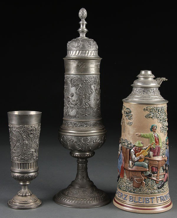 A LARGE GERMAN POLYCHROME EMBOSSED STONEWARE BEER: A LARGE GERMAN POLYCHROME EMBOSSED STONEWARE BEER STEIN, CIRCA 1900. Depicting a beer garden drinking scene together with a large presentation pokal with embossed scene of Augsburg and an embossed Aus