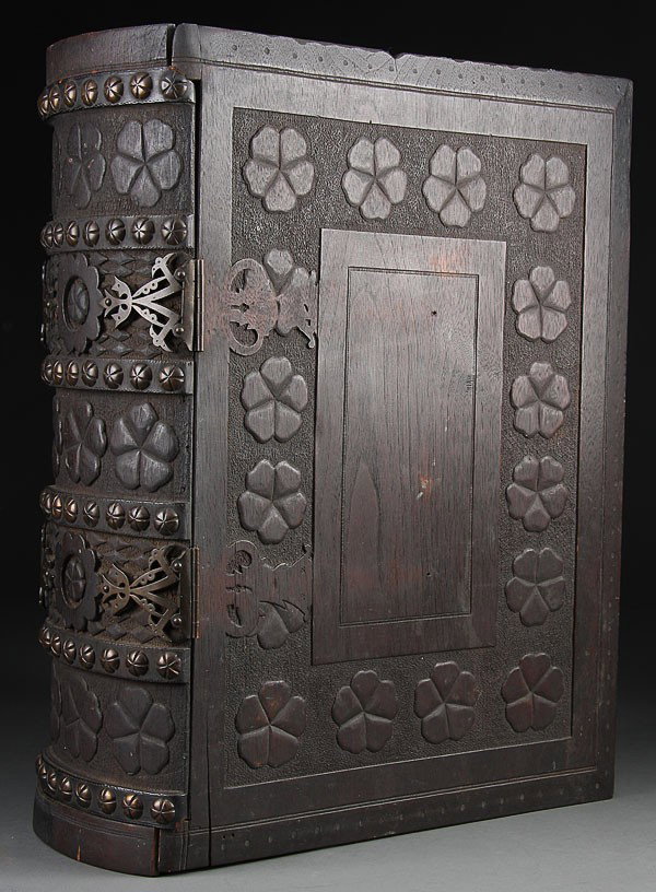 A LARGE AND IMPRESSIVE BLACK FOREST STYLE CARVED: A LARGE AND IMPRESSIVE BLACK FOREST STYLE CARVED WALNUT AND BRONZE MOUNTED BOOK FORM LIDDED BOX, CIRCA 1900. The double-hinged lid and end panel carved in the form of a book with rosette form designs,